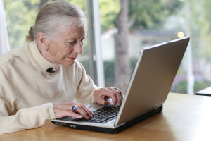 Elderly lady typing on laptop. Shallow DOF.